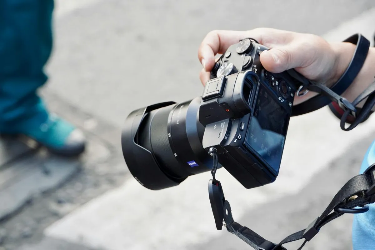 Photographer holding a Sony mirrorless camera with Zeiss lens on location