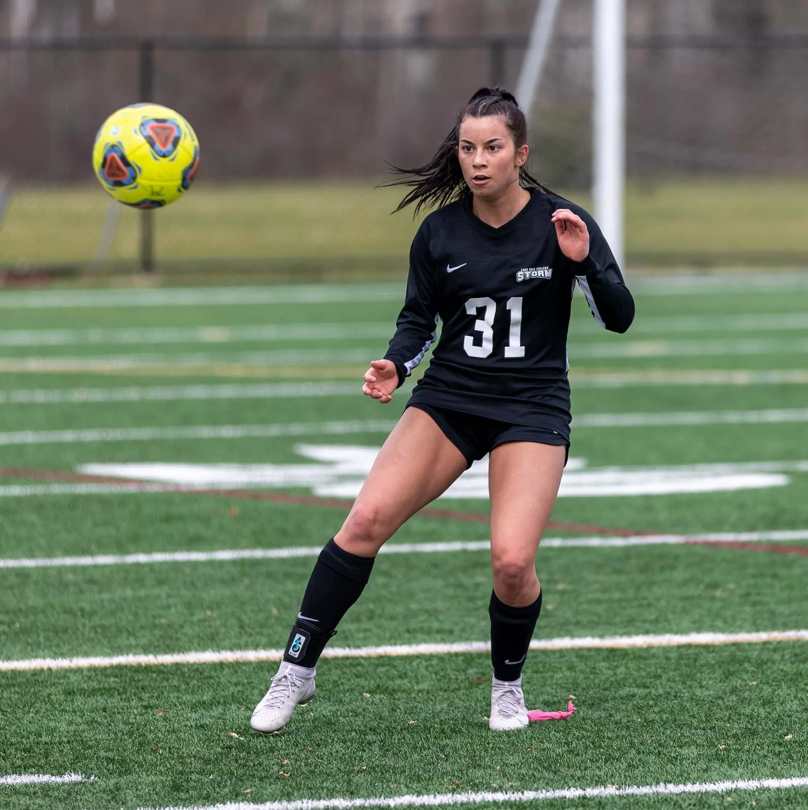 A soccer player in a black jersey, number 31, watching the ball closely as it approaches, anticipating her next move before contact.