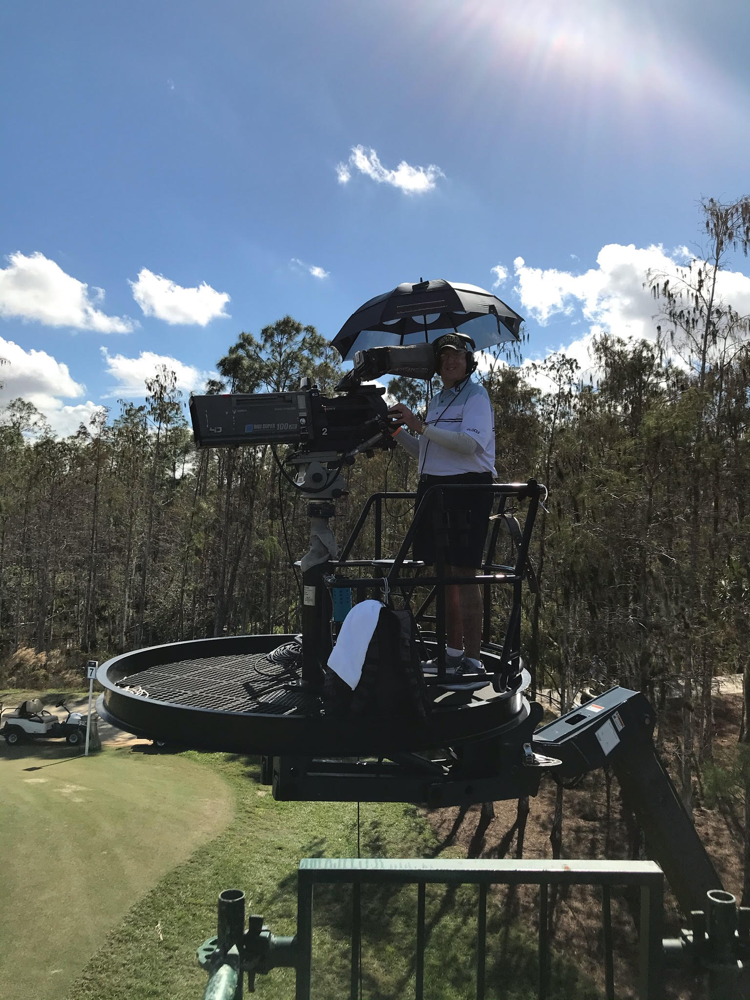 G Mark Bowden operating a broadcast camera on an elevated golf course platform